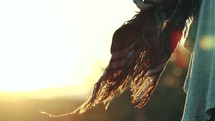 a woman holding a scarf blowing in the breeze at sunset 