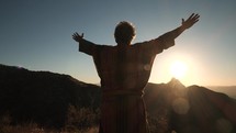 A Bible prophet praising God on a mountain top at sunset