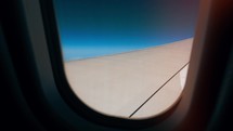 Airplane wing is seen through its window while flying. Airplane, Aircraft. Traveling by air.	
