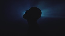 silhouette of a man's head in front of a spotlight 