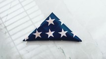 American flag folded in a triangle with red petals and flowers