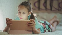 Kid child girl holding digital tablet. Teenager learning at home. Child Writing Homework for School, Girl Studying at Home, Homeschooling, Online Education. Modern Devices.