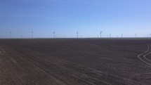 A wind farm on a vast farm field generating electricity