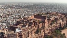Top view of Mehrangarh Fort exterior parallaxing with Jodhpur cityscape, Rajasthan, India - Aerial Panoramic Orbit shot 