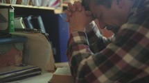 a man praying at his desk 