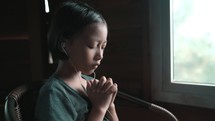 Girl praying with headphones in
