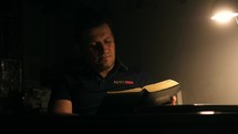 Man reading an Italian Bible alone in a dark room 