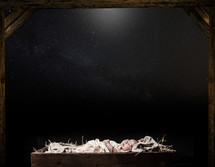 baby Jesus in a manger under stars in the night sky 