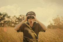 Shocked boy looking through binoculars