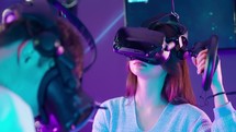 Over the shoulder view of a girl playing a virtual reality game wearing goggles.