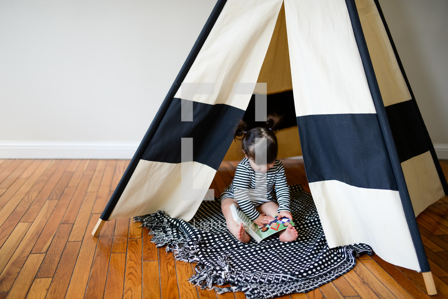a toddler girl playing in a play tent 