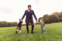 father dancing with his girls in a grassy field 