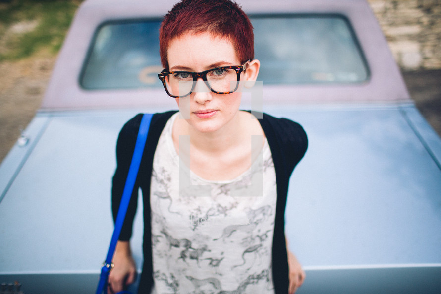 woman with a pixie haircut sitting on a car 