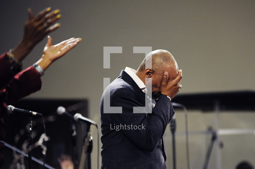 man covering his face at a worship service 