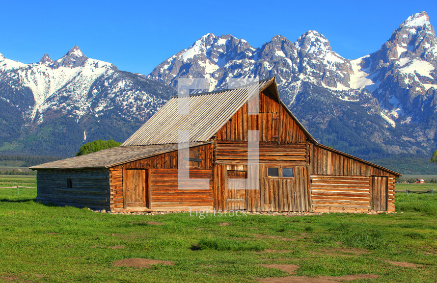 barn in front of snow capped mountains 