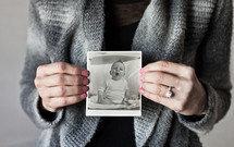 woman holding up an old baby picture