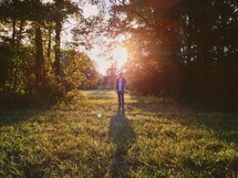 man standing in a forest clearing under intense sunlight