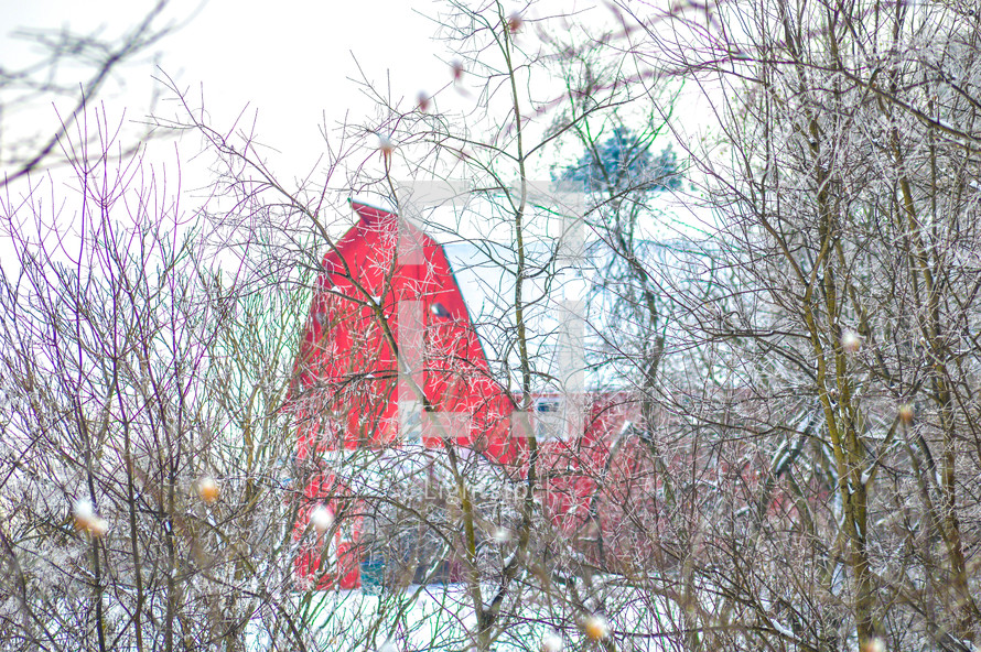 red barn in winter through branches 