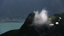 Misty cloud over green mountains in Interlaken Switzerland, turquoise lake and village in the background