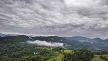 Grey rainy clouds moving over green rural country Aerial Time lapse
