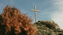 a woman praying on a mountainside looking up at a cross 