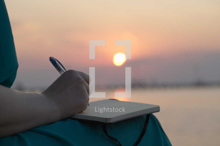 Woman writing in her diary at sunset