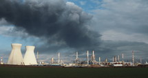 Accident in oil refinery - huge explosions and fireballs rising while thick black smoke covers the sky.