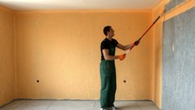 man with a roller painting a wall 