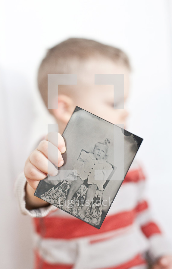 toddler boy holding an old photo