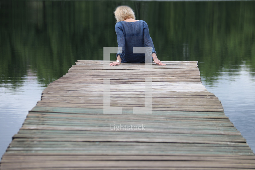 a woman sitting along on a pier 