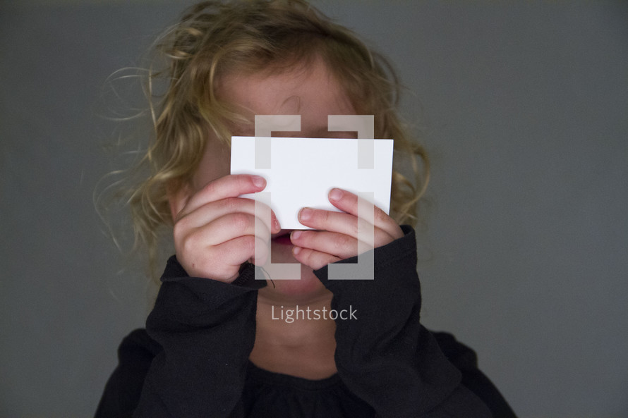 a girl holding up a blank notecard 