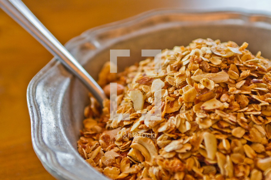 Spoon in a bowl of granola cereal.