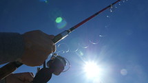 A fisherman reeling in line on a sunny day while fishing