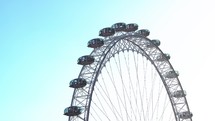 Low angle moving shot of London Eye ferris wheel over Thames River in London Great Britain