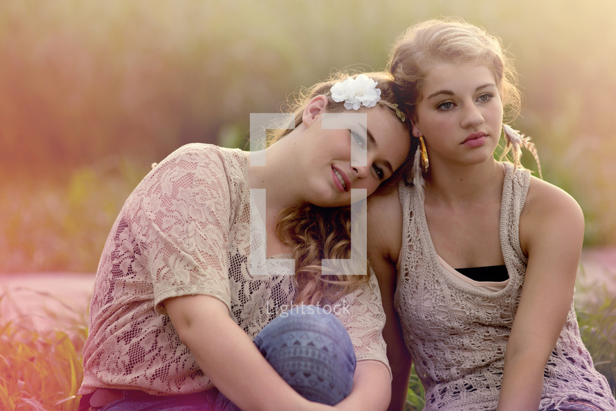 Two girls sitting in a field.