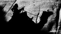 A shadow of a man riding a camel. 
