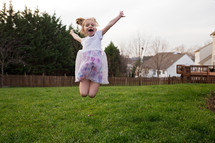 a girl jumping up in the backyard 
