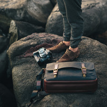 man standing on a rock and a camera and bag