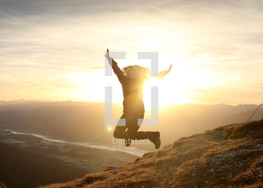 woman jumping for joy on a mountain top 
