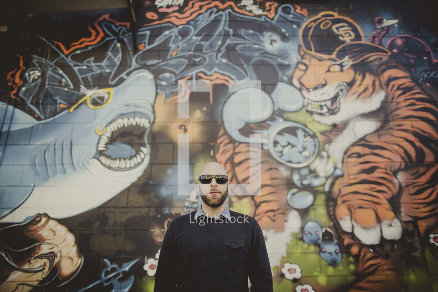 man standing in front of a graffiti covered wall