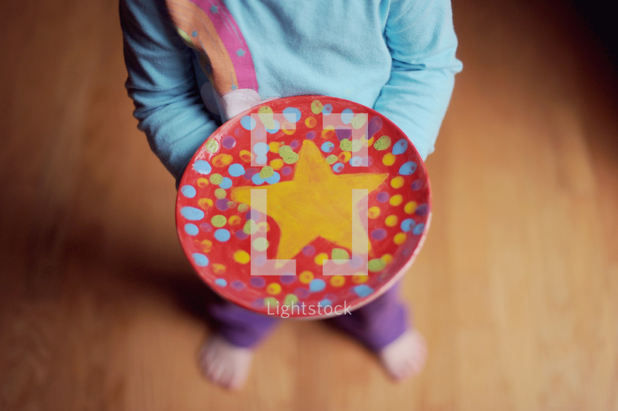 child holding a hand painted plate with a star 