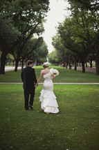 A bride and groom walking together in the grass