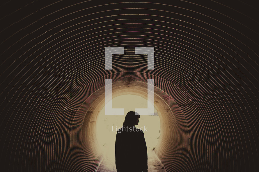 silhouette of woman standing in a tunnel