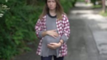 teen pregnancy, pregnant teen walking outdoors 