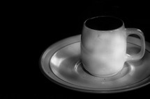 White cup and saucer on a black background.