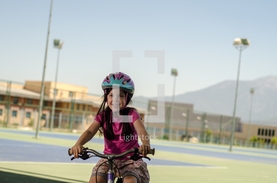 A young girl rides a bicycle near a school.