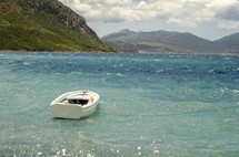 Boat in the ocean waves with mountains in the background.