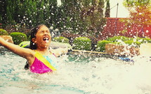 girl child splashing in a pool