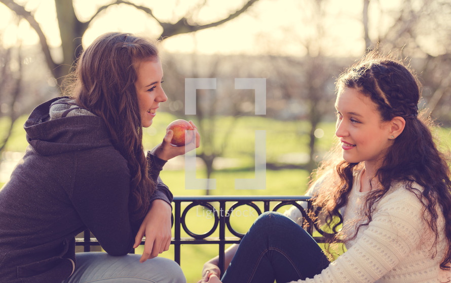 teen girls in conversation sitting outdoors 