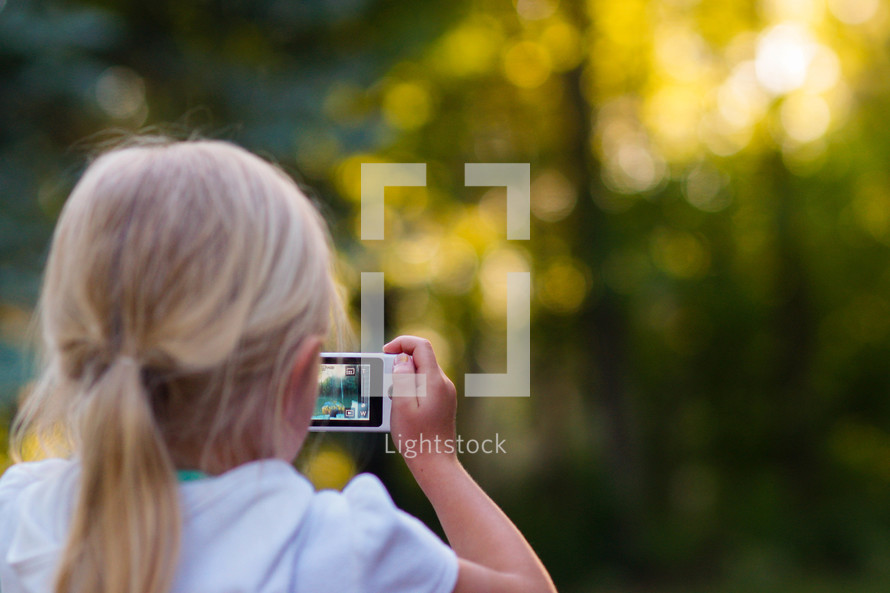 a girl child taking a picture with a cellphone 